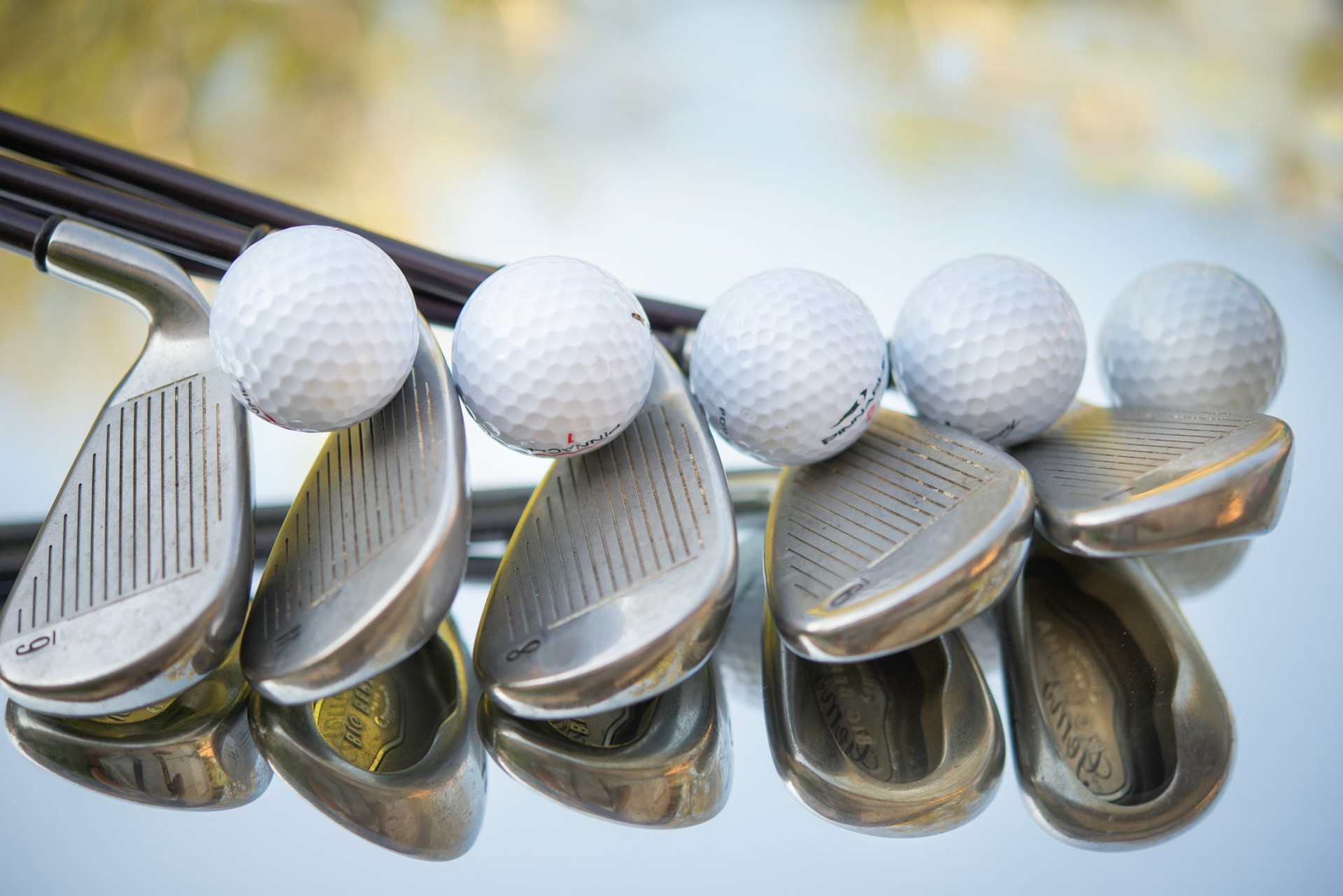 A row of golf clubs balancing golf balls on top