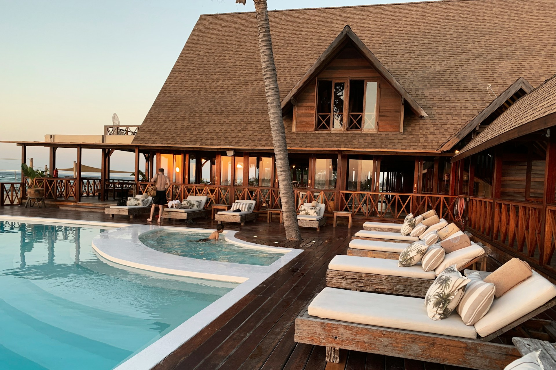 A pool with deck chairs and a cabin-style hotel